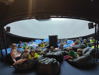 zdjęcie przedstawia ujęcie grupy dzieci z 0a i 0c w czasie wizyty planetarium